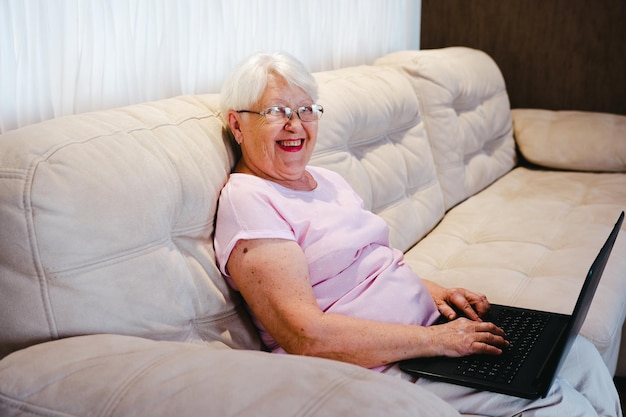 Mujer anciana feliz usando computadora portátil en casa Mujer mayor madura mayor viendo capacitación empresarial