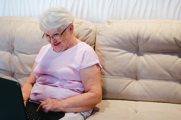 Mujer anciana feliz usando computadora portátil en casa Mujer mayor madura mayor viendo capacitación empresarial