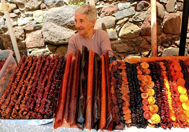 Foto mujer anciana sentada en un puesto de mercado