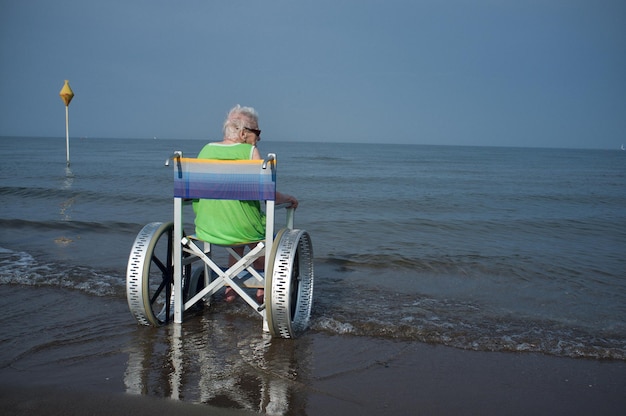 Foto mujer anciana en silla de ruedas en el mar