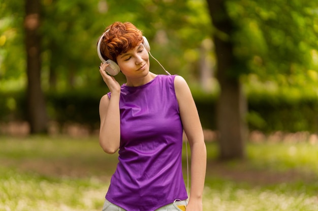 Mujer andrógina escuchando música y ajustando auriculares