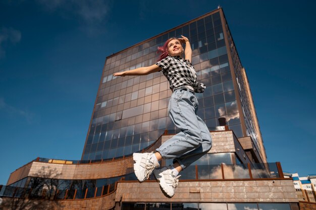 Foto mujer de ángulo bajo saltando en la ciudad