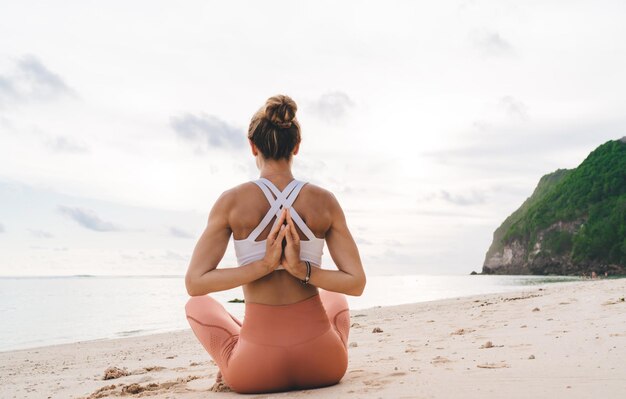 Mujer anónima meditando en posición Padmasana con las manos detrás de la espalda