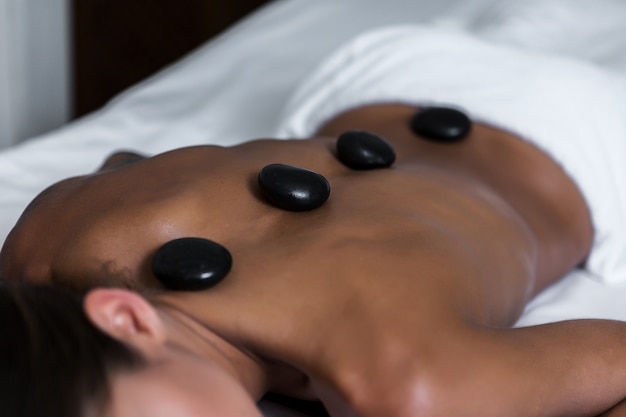 Mujer anónima con piedras calientes en el salón SPA