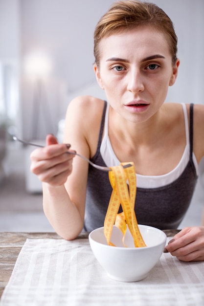 Mujer anoréxica. Triste mujer pálida pensando en la comida mientras está obsesionada con su peso