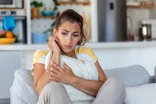 Mujer ansiosa y preocupada sentada en el sofá en casa Mujer frustrada y confundida siente problemas infelices en la pelea de la vida personal rompe con el novio y el concepto de embarazo inesperado