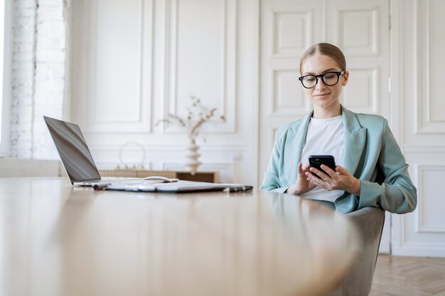 Foto una mujer con anteojos es una trabajadora independiente que usa una computadora portátil y hace un informe a una compañía financiera