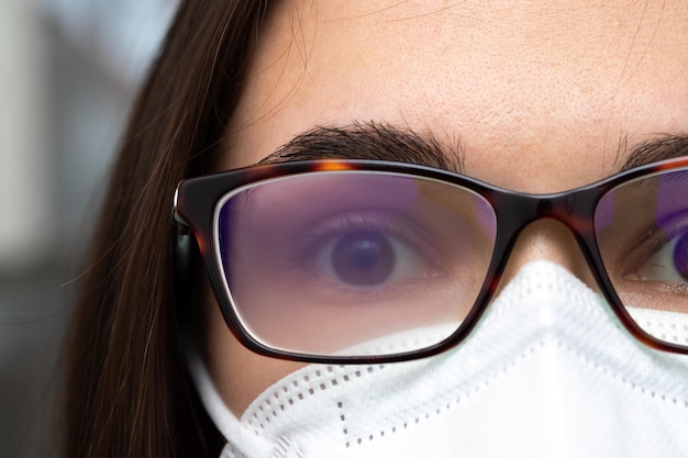 Mujer con anteojos y mascarilla mira directamente