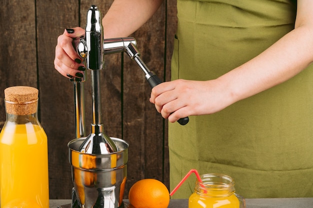 Mujer con aparato exprimidor de naranja en casa