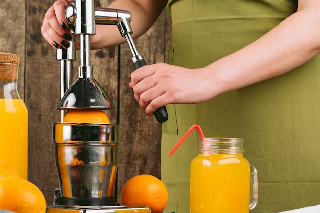 Foto mujer con aparato exprimidor de naranja en casa