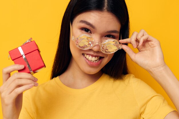 Mujer con apariencia asiática con cajas de regalo en las manos modelo de estudio posando divertido inalterado