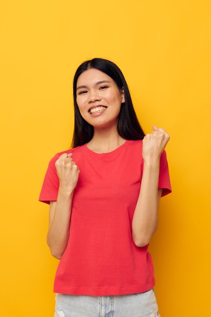 Mujer con apariencia asiática en una camiseta roja posando emociones divertidas fondo amarillo inalterado