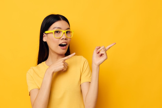 Mujer con apariencia asiática en gafas gesticulando con las manos copyspace fondo amarillo inalterado