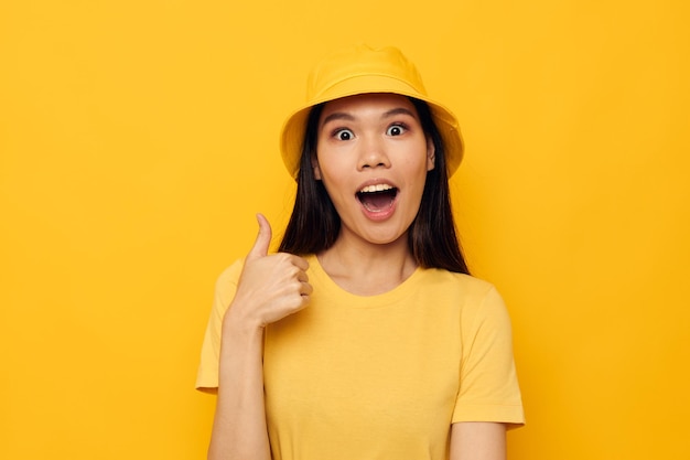 Mujer con apariencia asiática con un sombrero amarillo posando emociones fondo aislado inalterado