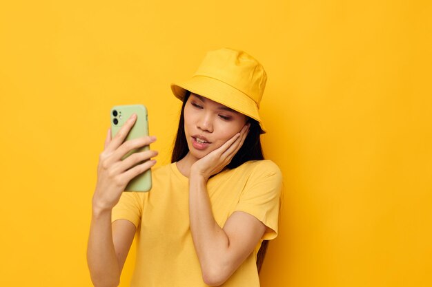 Mujer con apariencia asiática sosteniendo un teléfono posando tecnología de estilo de vida aislado fondo inalterado