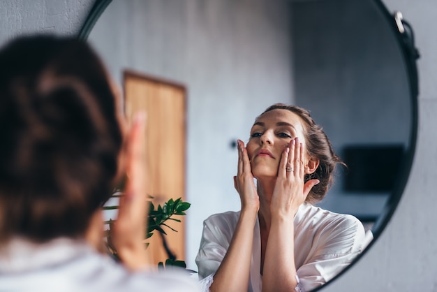 La mujer aplica espuma a su rostro, limpiando su piel.