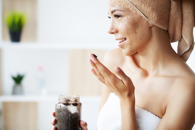 La mujer aplica un exfoliante de café en la cara.