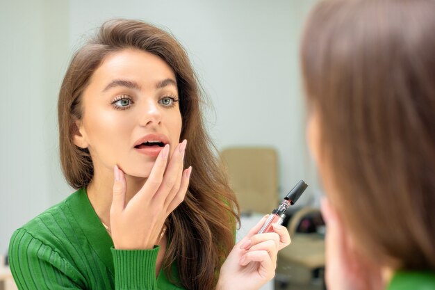 La mujer aplica lápiz labial en los labios