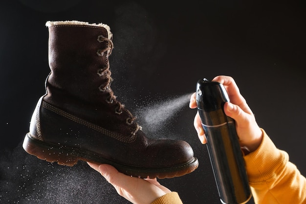 Una mujer aplica el spray a las botas de invierno de mujer nubuck marrón