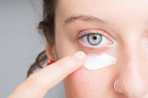 Mujer aplicando una crema blanca en la cara