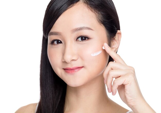 Mujer aplicando crema cosmética en la cara