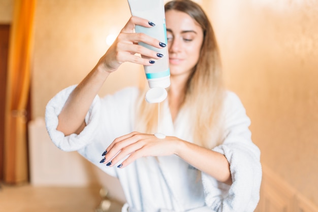 Mujer aplicando crema cosmética para manos, cuidado de la piel en el baño. Cuidado corporal e higiene, sanidad, productos de belleza