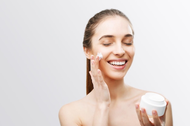Foto mujer aplicando crema facial en ella