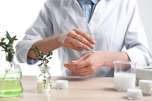 Mujer aplicando crema natural en la mano en primer plano de laboratorio cosmético