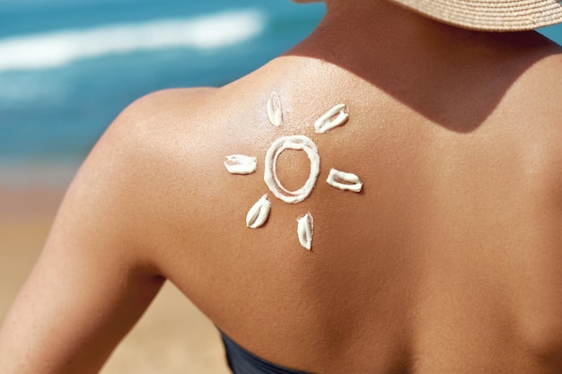 Mujer aplicando crema solar en el hombro bronceado en forma de protección solar Sun