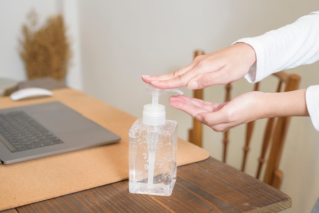 Foto la mujer está aplicando gel desinfectante a las manos en la mesa de trabajo