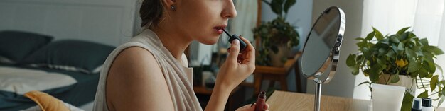 Mujer aplicando lápiz labial en un dormitorio moderno