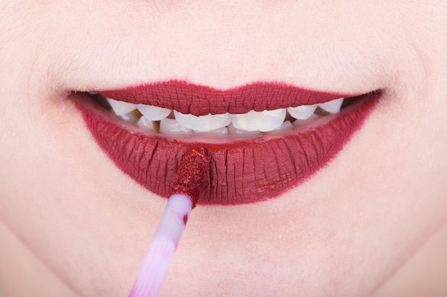 mujer aplicando lápiz labial rojo en sus labios