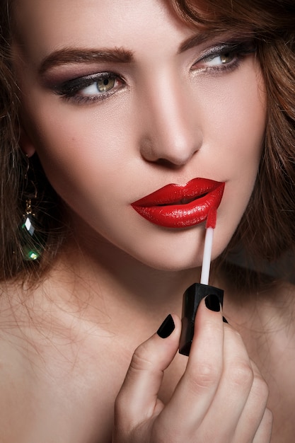 Mujer aplicando lápiz labial rojo