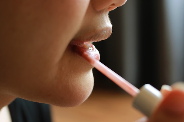 mujer aplicar lápiz labial en su labio