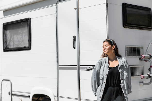 Mujer apoyada en camper con los ojos cerrados