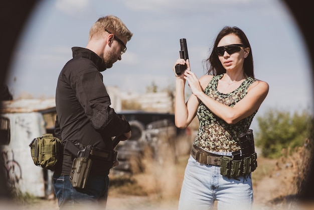 Foto una mujer aprende a disparar una pistola en un campo de tiro con un instructor