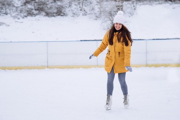 La mujer aprende a esquiar en la pista de hielo de la ciudad