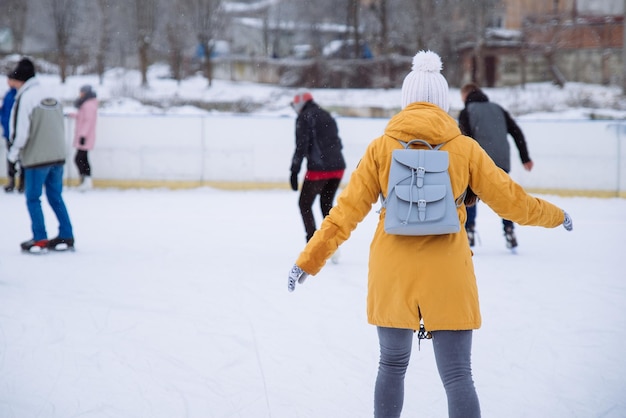 La mujer aprende a esquiar en la pista de hielo de la ciudad