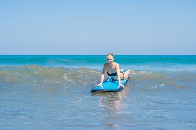 Una mujer aprende a surfear en la espuma. Bali, Indonesia