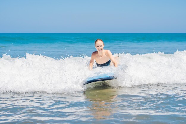 Una mujer aprende a surfear en la espuma. Bali, Indonesia