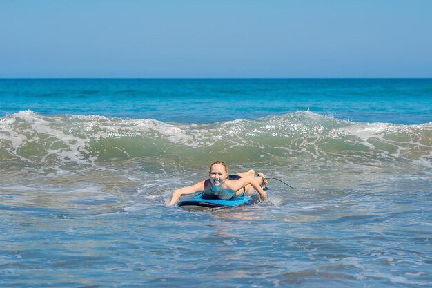 Una mujer aprende a surfear sobre la espuma. Bali, Indonesia