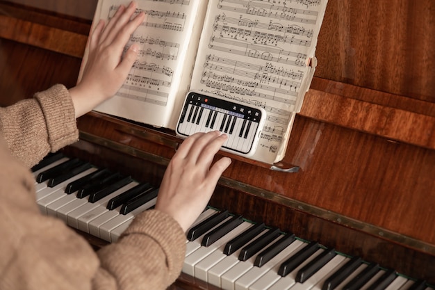 La mujer aprende a tocar el piano usando el teléfono, lección de música, formación en línea.