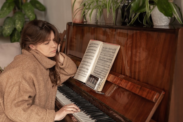 La mujer aprende a tocar el piano usando el teléfono, lección de música, formación en línea.