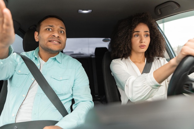 Mujer aprendiendo a conducir un coche con un profesor de conducción descontento