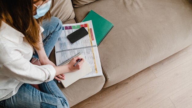 Mujer aprendiendo idiomas extranjeros en casa con máscara