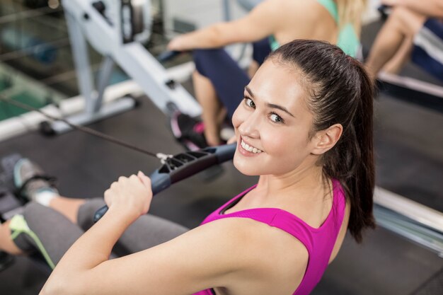 Mujer apta en la máquina de dibujo en el gimnasio