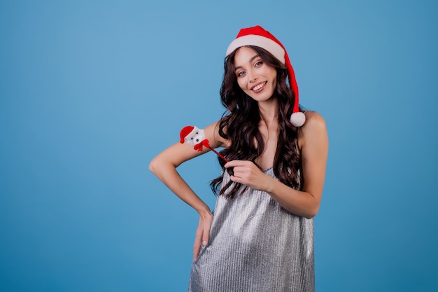 Mujer apuntando a copyspace con pluma con sombrero de navidad