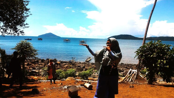 Foto mujer apuntando mientras está de pie contra el mar en la playa