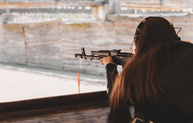 Mujer apuntando con un rifle de francotirador al objetivo en el campo de tiro en un día soleado