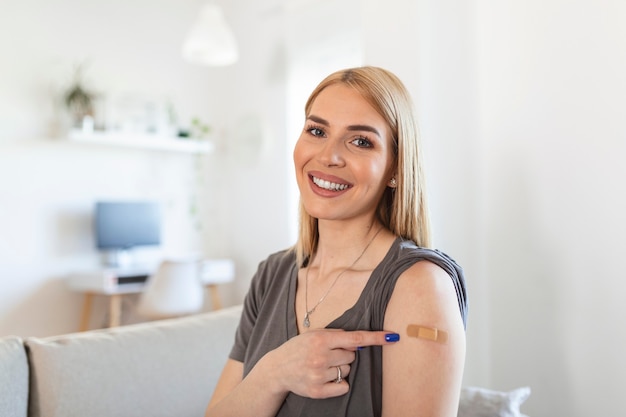 Mujer apuntando a su brazo con un vendaje después de recibir la vacuna covid-19. Mujer joven mostrando su hombro después de recibir la vacuna contra el coronavirus